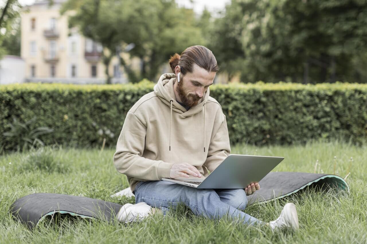 A young man doing his online learning at the park.