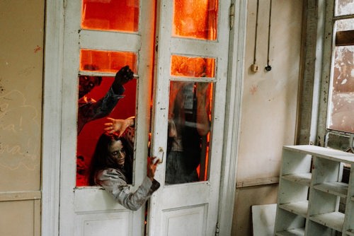 People dressed up as zombies trying to break through a door in a house