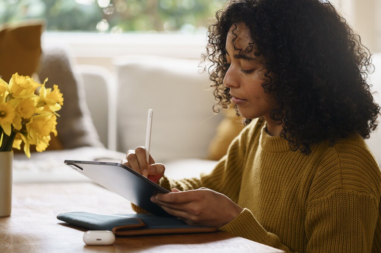 Young HR professional using a tablet to take notes at a table, by the window