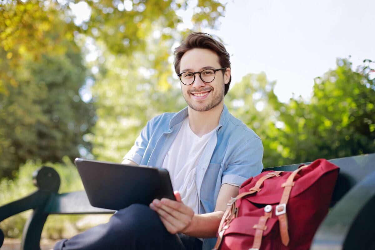 Young man studying in his tablet while sitting outside