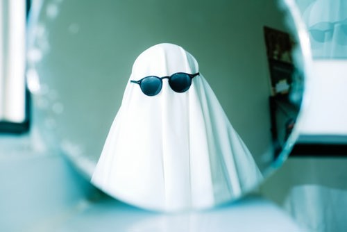 A person dressed up as a ghost in a white sheet wearing sunglasses