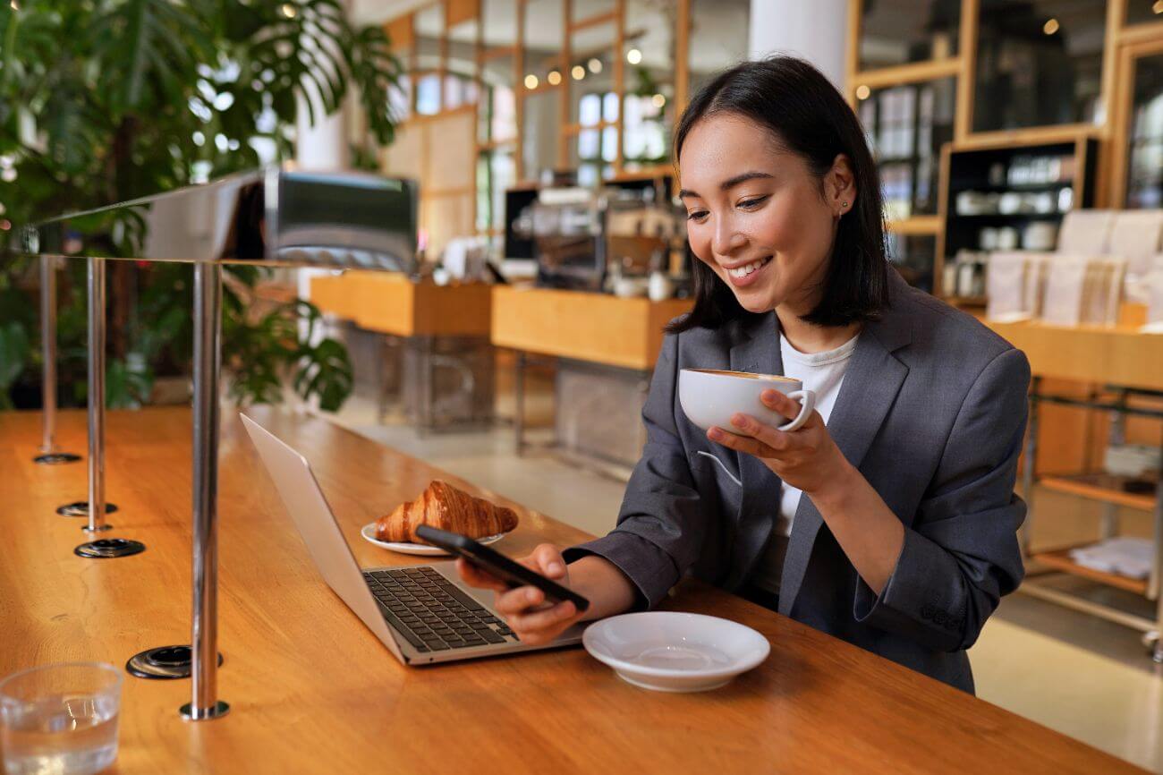 Young woman having a coffee while checking the best leadership blogs to follow