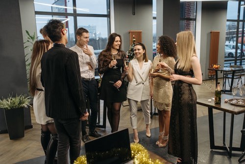 A group of male and female employees stood in a circle with drinks at a Christmas party